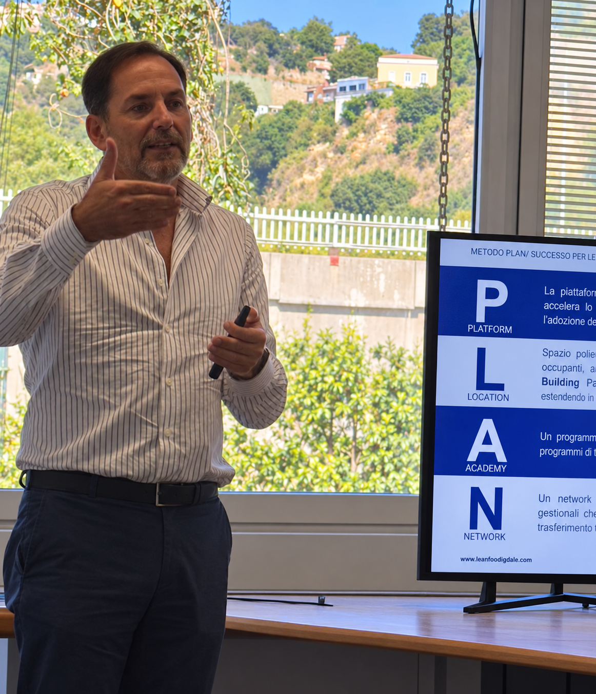 Un relatore presenta il metodo PLAN davanti a uno schermo