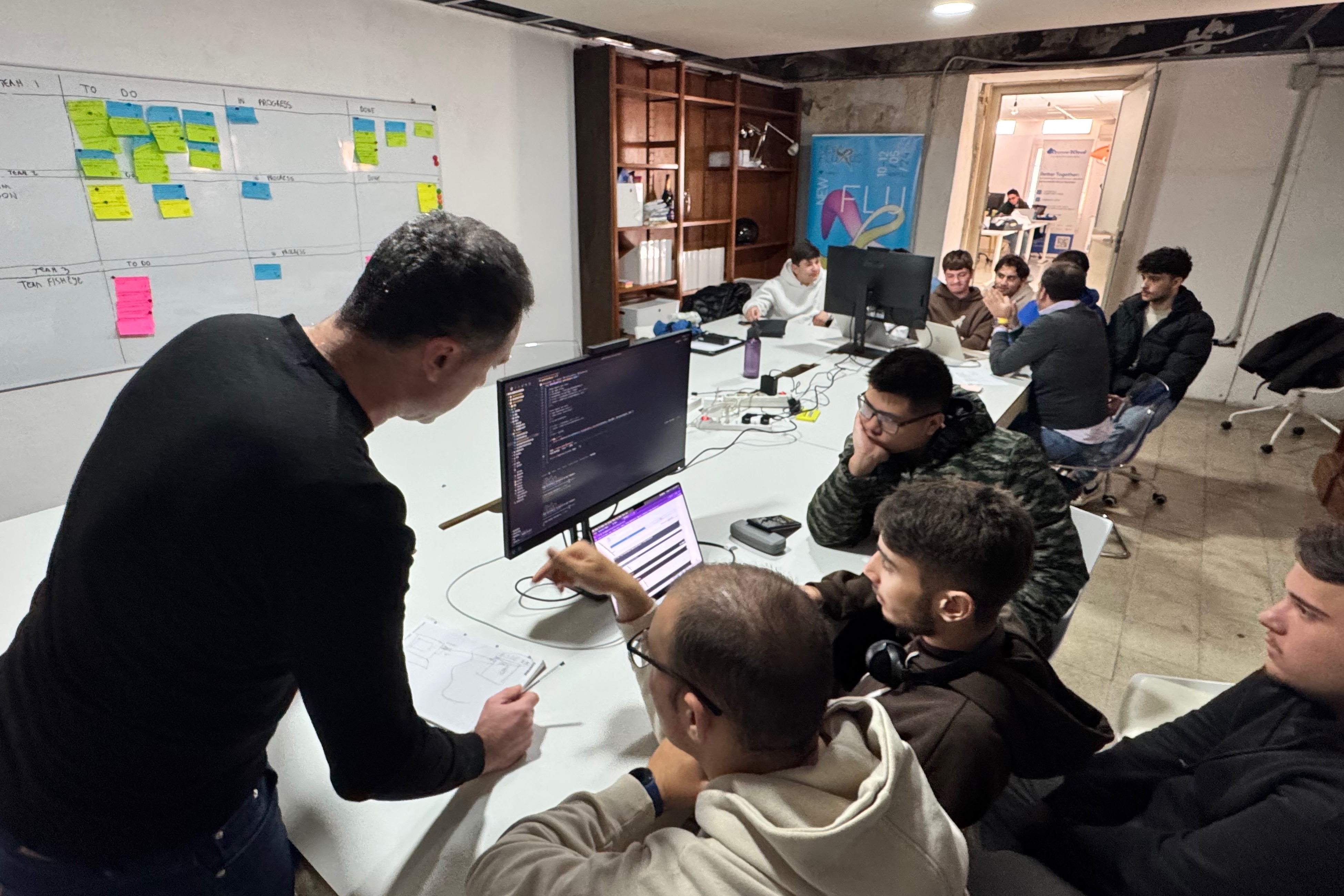 Students around a table, with the task board on the wall
