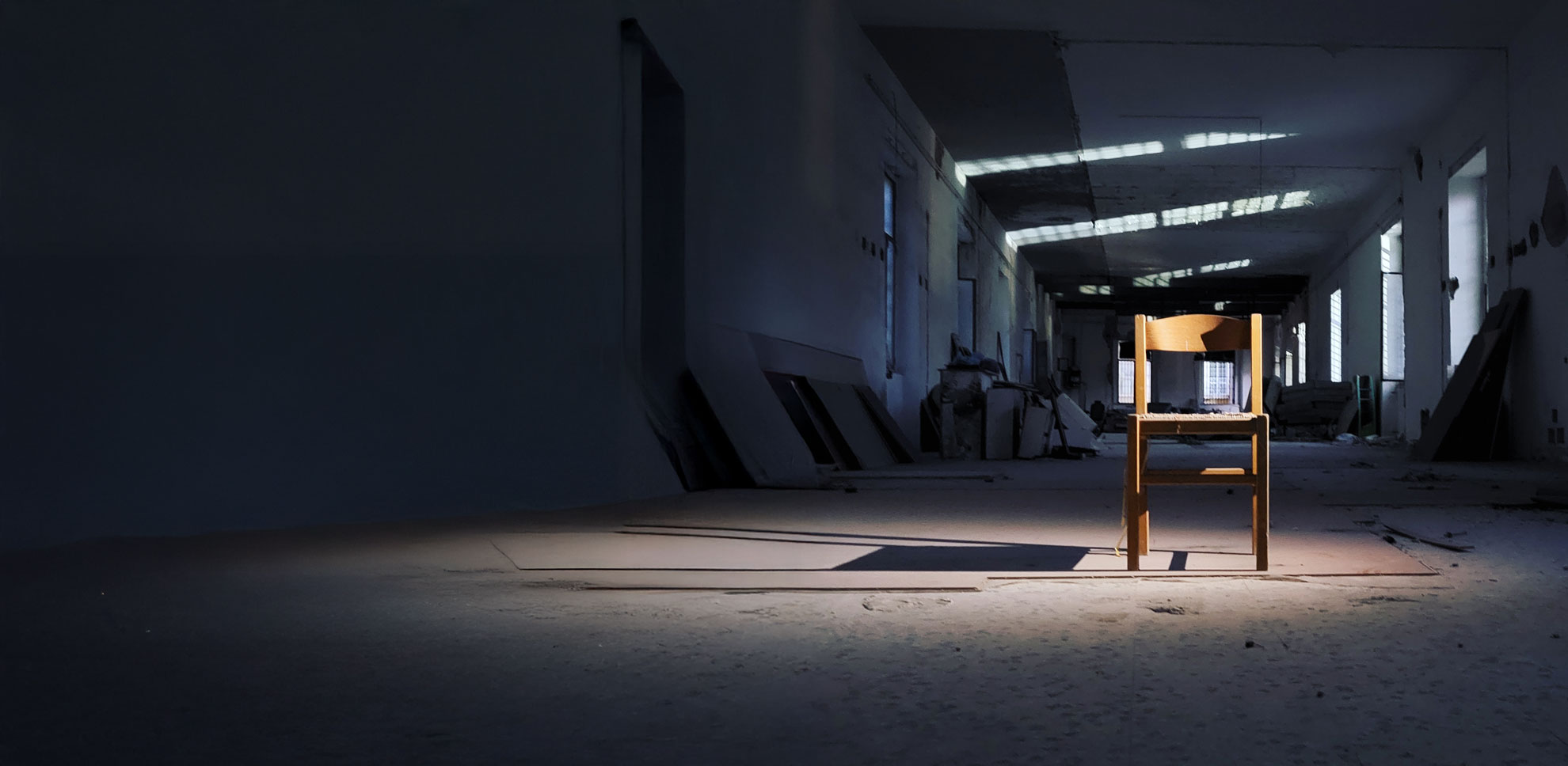 The empty hall of the Ex Lanificio Borbonico, a single chair in raking light
